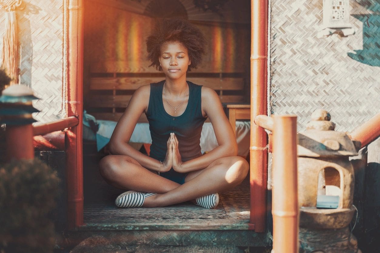 Woman meditating in a cozy, warm-toned room.
